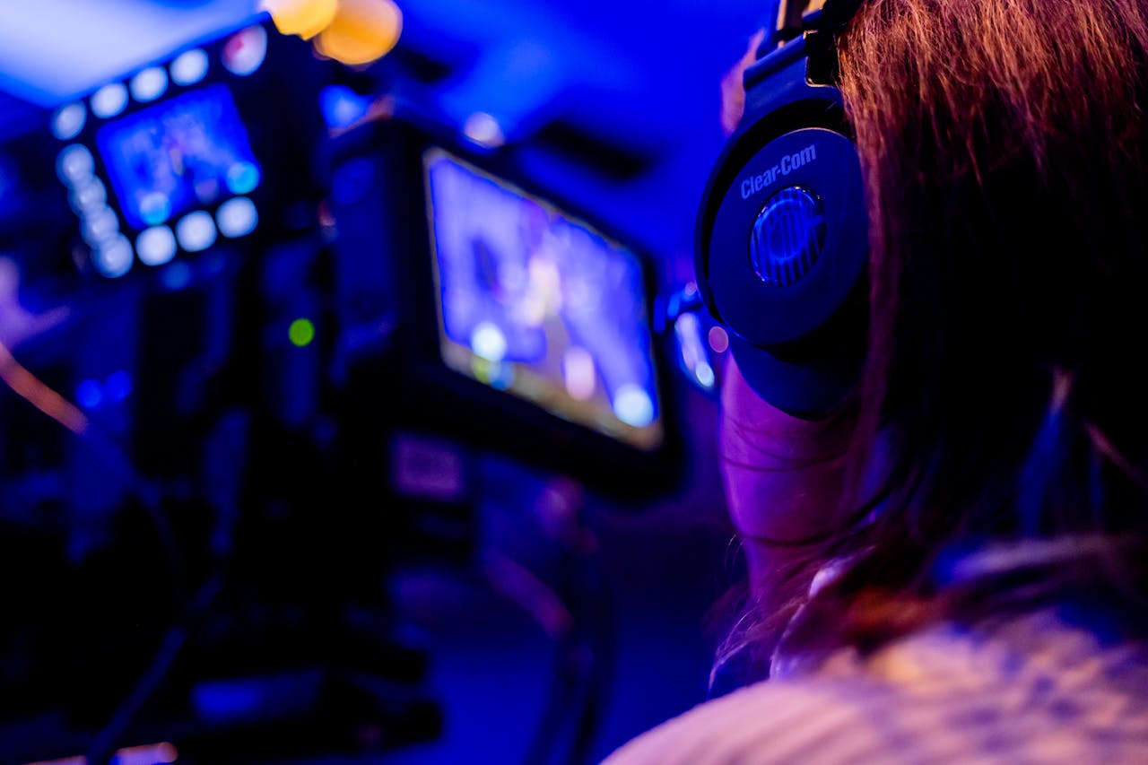A person wearing headphones operates a camera in a vibrant studio environment.