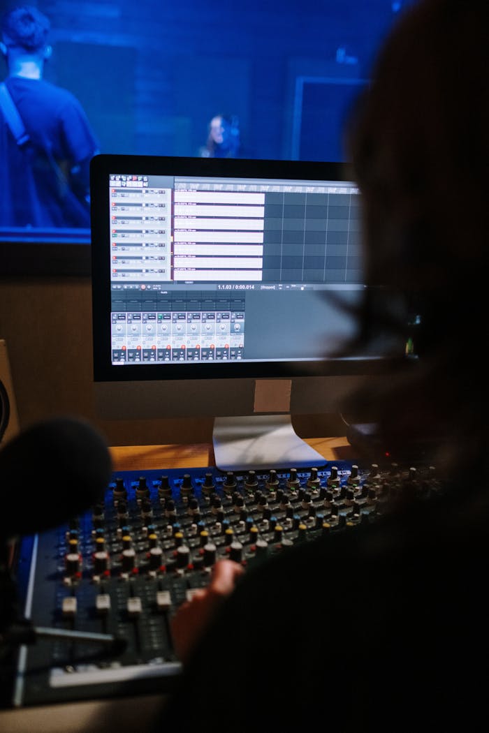 A recording artist working on audio mixing at a sound studio workstation.